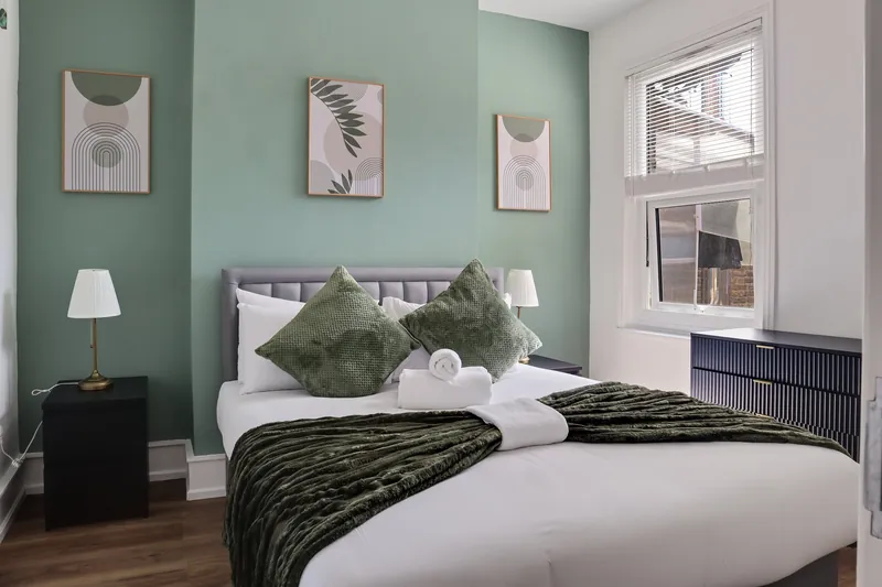 Bedroom with sage green wall and botanical prints